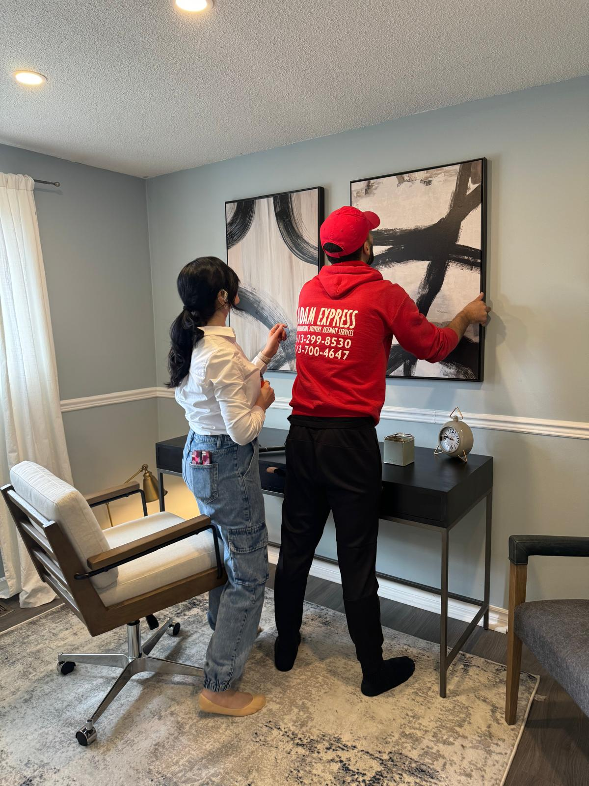 Ottawa Elite and Adam Express team positioning framed artwork in a staged living room